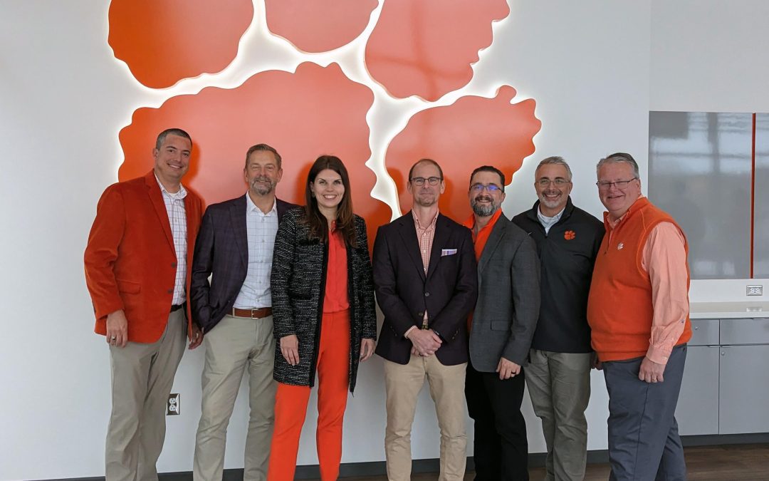 Team members from Garvin Design Group and HNTB pose in front of a backlit tiger paw wall feature at the recently completed Clemson's Womens Sports Programs Expansion.
