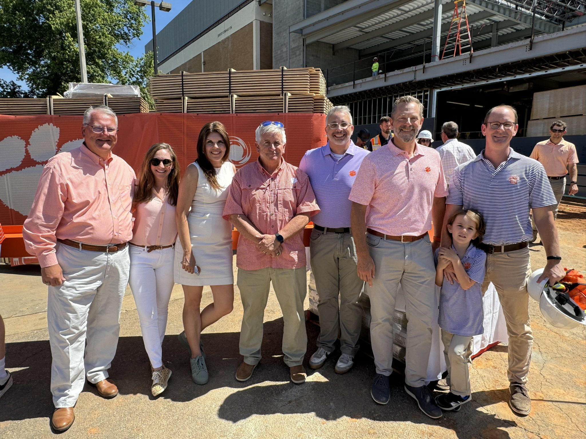 A picture of a group of people standing on a construction site wearing orange, white, and purple.