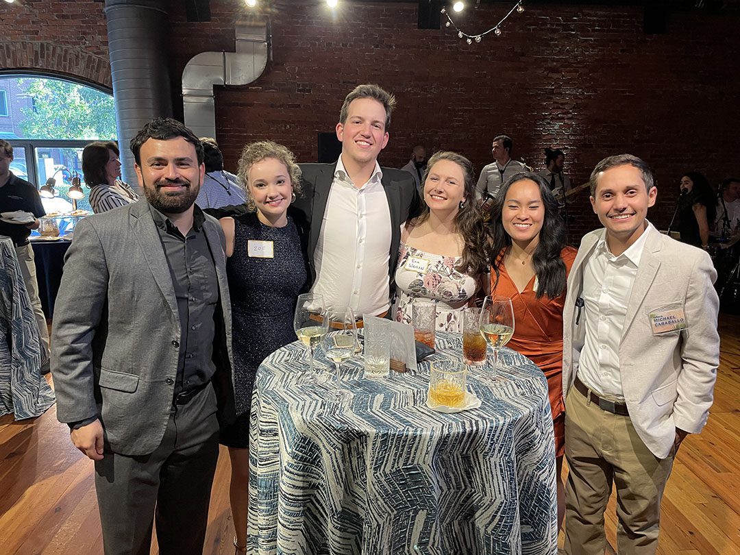 A photo of Michael Caraballo with friends at a party inside a brick building with hardwood floors