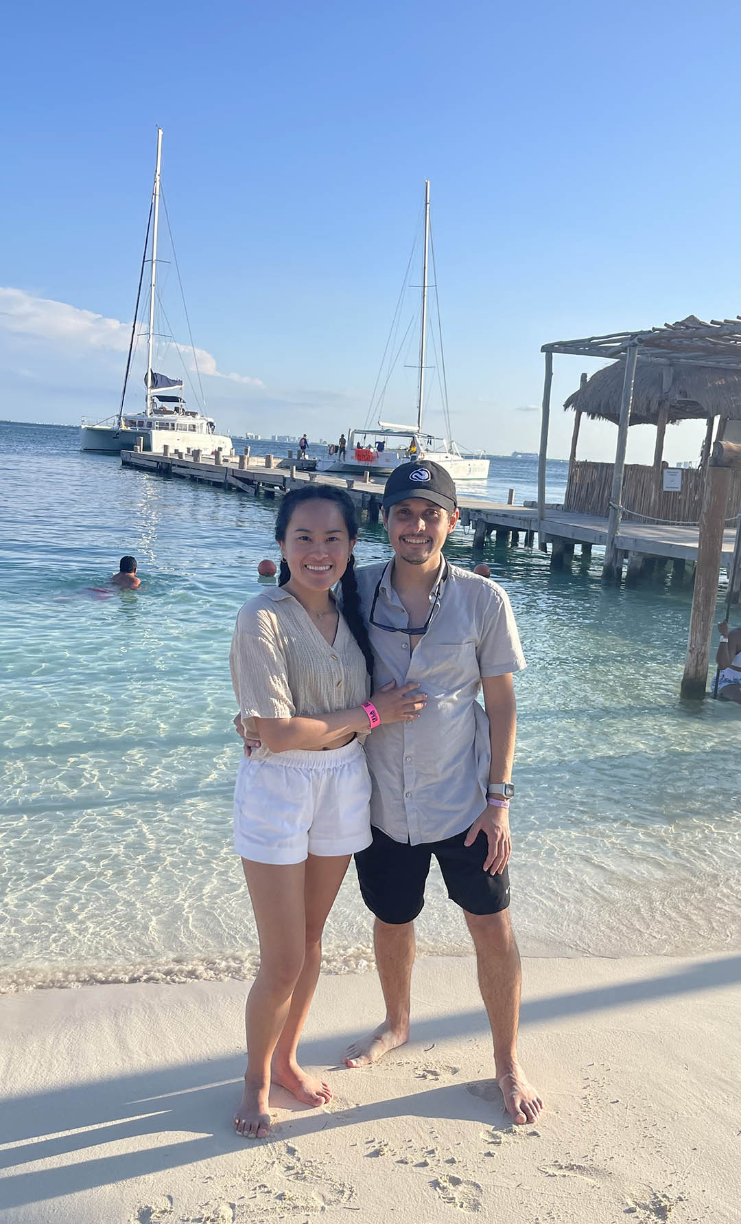 A photo of Michael Caraballo and his girlfriend at the beach with sailboats in the background